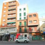 a car parked in front of a building with many balconies